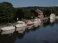 The Troy (Federal) Lock on the Hudson River (top left), the New York skyline as seen from the Hudson River (top middle), a line of boats on the Erie Canal (top right), and the Waterford, N.Y., Harbor Visitor Center, at the junction of the Hudson River and Erie Canal (bottom). Photo by Dick allen